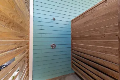 Perfect for rinsing off after the Pool or Beach! This stylish and private Outdoor shower  is built with rustic wood screens and vibrant coastal siding, offering a convenient and refreshing end to your day.