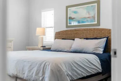This inviting bed features a striking woven rattan headboard and calming coastal artwork. It is flanked by matching nightstands and lamps, ensuring a restful and stylish retreat.