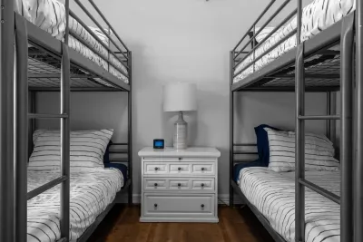 Perfect for groups or kids! This fun room features two sets of sturdy metal bunk beds with comfortable striped bedding. A central dresser provides storage and light for a cozy, memorable sleepover.