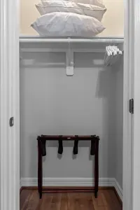 A tidy closet ready for guests! It provides easy clothing storage , a wooden luggage rack for unpacking, and is stocked with extra hangers and extra pillows  for a comfortable stay.