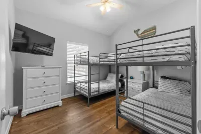 Perfect for a fun group stay! This room features two sets of metal bunk beds, a large mounted TV , and a white dresser for ample clothing storage. The vaulted ceiling and ceiling fan  keep this inviting space comfortable for all.