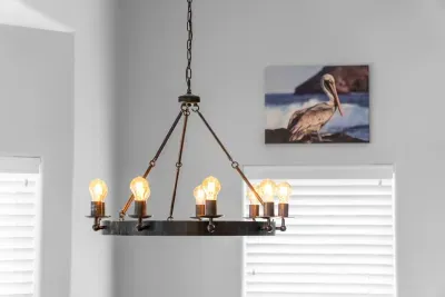 This rustic, multi-bulb chandelier is the charming centerpiece of the dining area. It provides a warm glow for meals, complemented by calming coastal art.