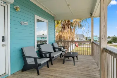 Enjoy beautiful views from the Upper Deck/Balcony! This raised wooden deck features stylish gray cushioned sofas and a table, perfect for relaxing in comfort and enjoying the coastal air.