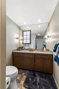 Clean lines and soft tones come together in this full bathroom, featuring warm brown cabinetry, marble tile accents, and a bright, refreshing atmosphere.