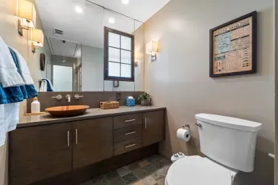 This full bathroom offers a serene retreat with rich cabinetry, marble accents, and thoughtful amenities like fresh towels, toiletries, and a spacious shower for a comfortable stay.