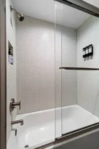 This full bathroom offers a serene retreat with rich cabinetry, marble accents, and thoughtful amenities like fresh towels, toiletries, and a spacious shower for a comfortable stay.