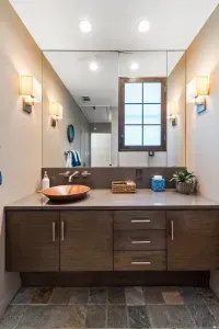 This full bathroom offers a serene retreat with rich cabinetry, marble accents, and thoughtful amenities like fresh towels, toiletries, and a spacious shower for a comfortable stay.