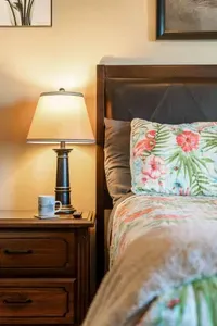 Warm, relaxing bedroom with soft coastal bedding and bedside lamp lighting—perfect for unwinding with a cup of coffee and getting a restful night’s sleep.