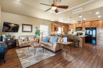Spacious open-concept living area with comfy seating, a large TV, and plenty of natural light—flowing right into the fully equipped kitchen with bar seating, perfect for gathering, meals, and relaxing together.