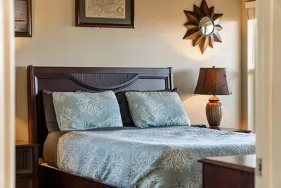 Relax in this cozy coastal bedroom with a comfortable bed, soft linens, and warm lighting—perfect for unwinding after a day at the beach.