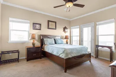 Peaceful primary bedroom with a comfy king bed, soft coastal decor, and plenty of natural light—plus private deck access for fresh air and relaxing views.