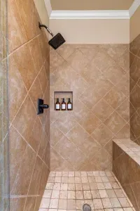 Spa-like walk-in shower with beautiful tile, a built-in bench, and convenient shampoo/soap nook—perfect for rinsing off after a day at the beach.