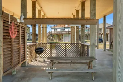 Covered outdoor space with a picnic table and charcoal grill—perfect for cookouts, family meals, and relaxing in the shade after a day at the beach.