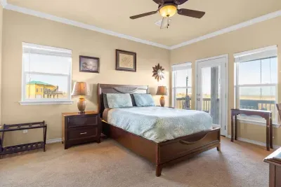 Spacious primary bedroom with a comfy king bed, coastal decor, and plenty of natural light—plus direct access to the deck for morning coffee and beautiful views.