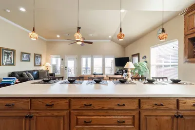 Huge kitchen island with bar seating and pendant lighting, overlooking the open living area—perfect for serving meals, hosting game nights, and keeping everyone together in one spacious, beach-ready gathering spot.