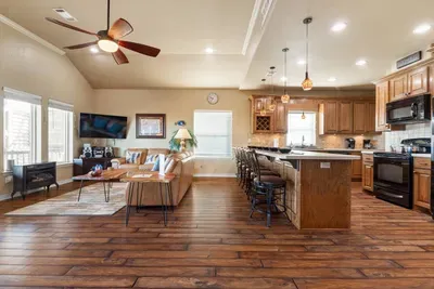Spacious open-concept layout with a bright living room, large TV, and plenty of seating—plus a fully equipped kitchen with a big island and bar stools, perfect for cooking, gathering, and making memories together.