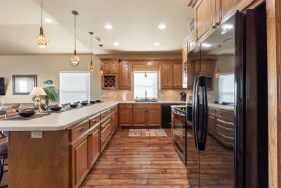 Spacious, fully equipped kitchen with beautiful wood cabinetry, a large island with bar seating, modern appliances, and plenty of counter space—perfect for cooking big family meals or prepping snacks for the beach.