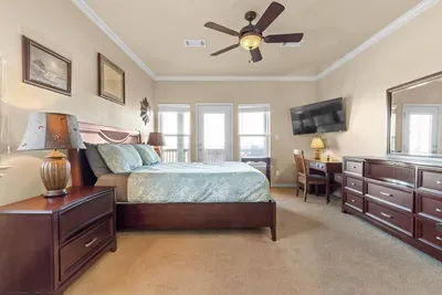 Relax in the spacious primary suite featuring a comfortable king bed, flat-screen TV, and plenty of room to unpack—plus deck access and natural light for the perfect beach getaway.