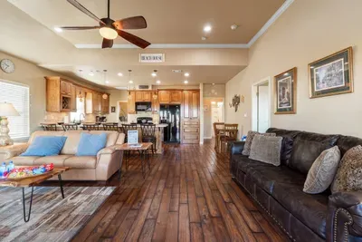 Open-concept great room with cozy seating, high ceilings, and a ceiling fan—flowing into the fully stocked kitchen with bar seating, perfect for relaxing together, cooking meals, and making memories.