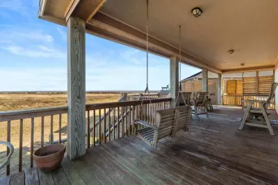 Covered deck with a porch swing and plenty of seating—perfect for relaxing in the shade while enjoying the coastal breeze and views.