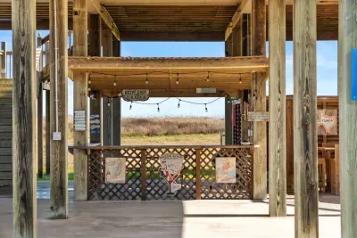 Outdoor hangout area under the house with string lights and a fun bar-style setup—perfect for relaxing, grilling, and gathering with friends after a day at the beach.