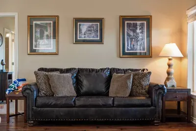 Relax in a cozy living room with a plush leather sofa, soft throw pillows, warm lighting, and tasteful wall art—perfect for movie nights or unwinding after a day at the beach.