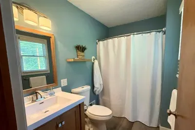 Attached to the primary bedroom this bathroom offers a shower/tub, sink, vanity, toilet, fresh towels, and shampoo, conditioner, and body soap. 