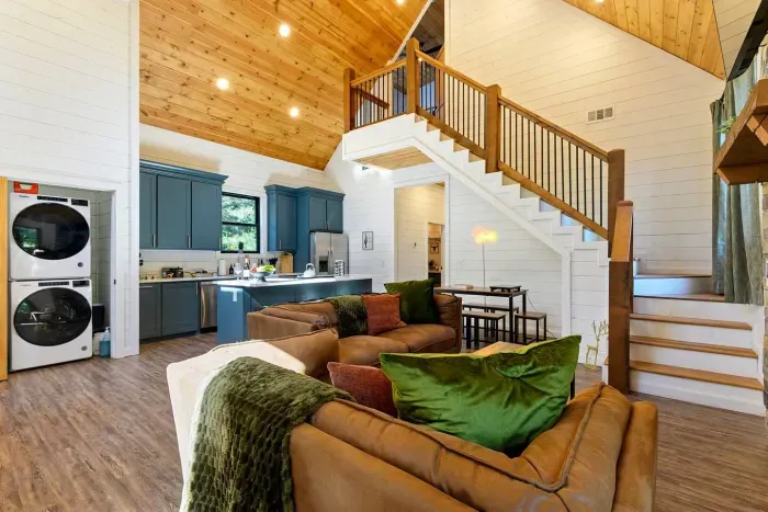 [Main Level] Open floor plan living room, kitchen, dining room, providing ample space and light with incredibly high ceilings. Washer/Dryer just off kitchen