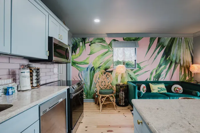Tropical-chic kitchen and lounge with bold mural and velvet seating