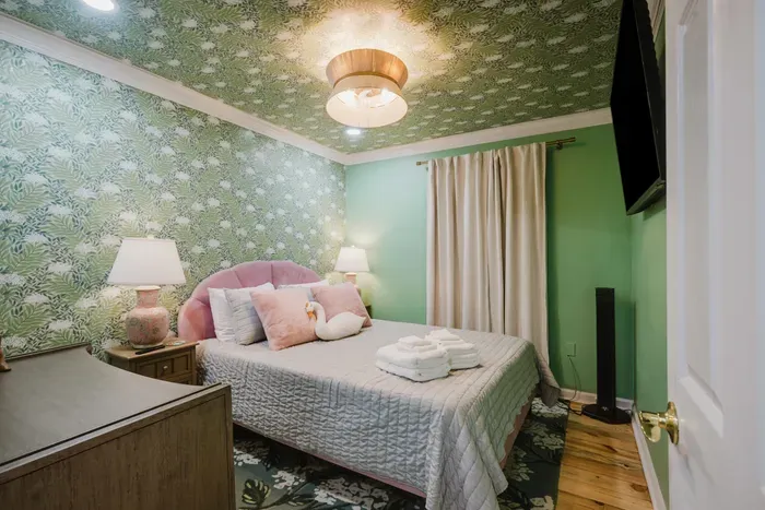 Chic tropical bedroom with plush bedding, TV, and stylish boutique vibes