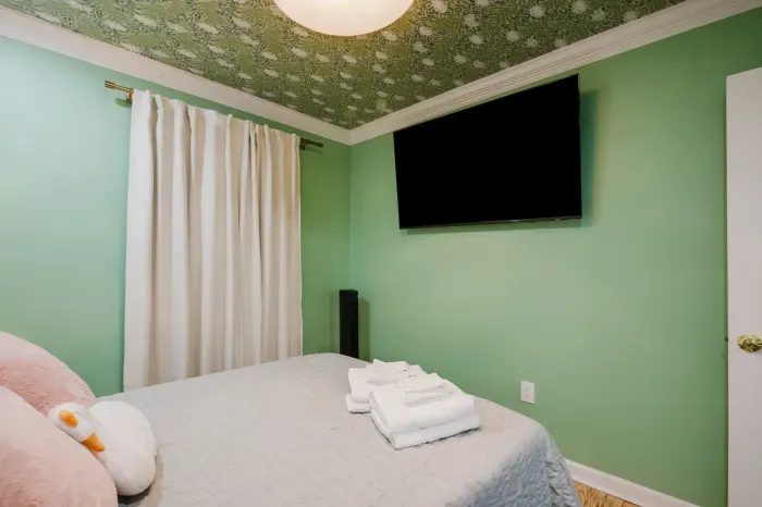 Cozy bedroom with bold designer ceiling and large wall-mounted TV