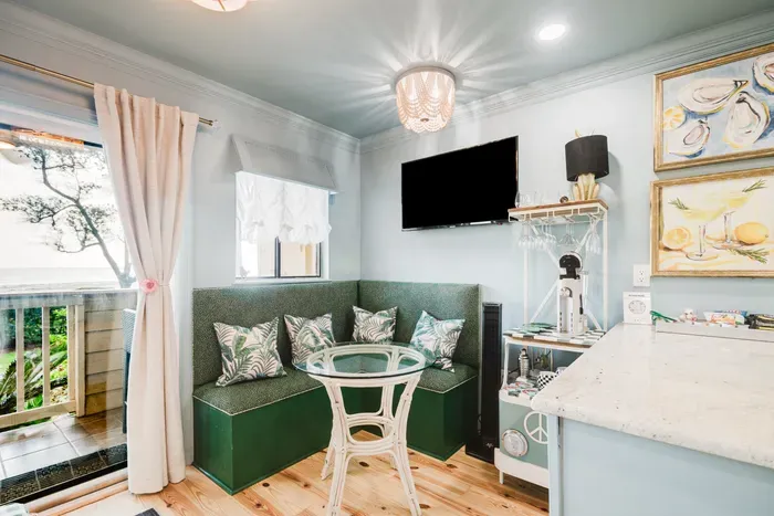 Cozy breakfast nook with balcony access, TV, and stylish coastal charm