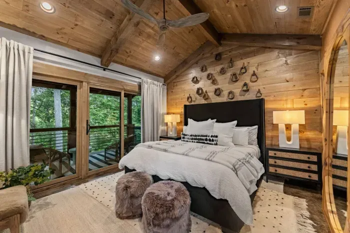 This vaulted bedroom features warm woods & curated design accents that create an elevated cabin feel. The plush king bed dressed in crisp linens promises restful nights while the balcony doors open to a canopy of trees - a true Blue Ridge escape.