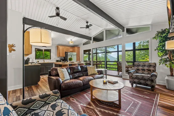 BVaulted ceilings, a wall of windows, and an actual Smokies ridgeline out the glass. Kitchen, living, and screened porch all open to each other up here.
