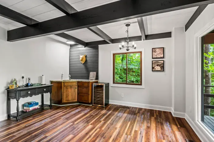 Wet bar with granite counter, sink, and wine fridge. Barware's stocked and the games are on the shelf below.