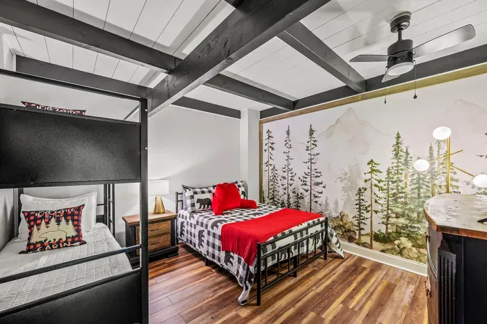 Full bed plus a twin-over-twin bunk under a hand-painted forest mural. Sleeps four in one room without feeling like a barracks.