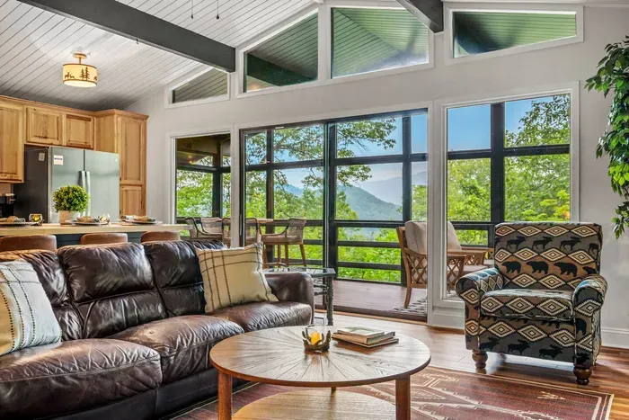 Vaulted ceilings, a wall of windows, and an actual Smokies ridgeline out the glass. Kitchen, living, and screened porch all open to each other up here.