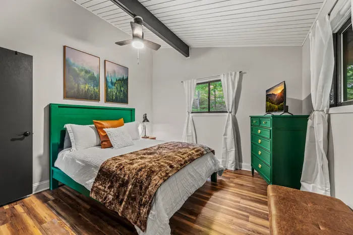 Faux fur throw, leather bench at the foot of the bed, curtains pulled back to the green. Small luxuries in every room.