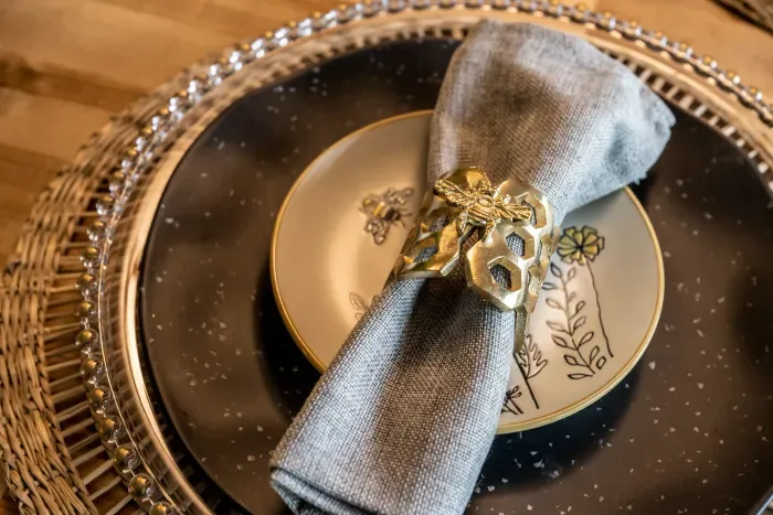 Bee-print salad plates, gold honeycomb napkin rings, woven chargers. We didn't have to go this hard on the table settings. We did anyway.