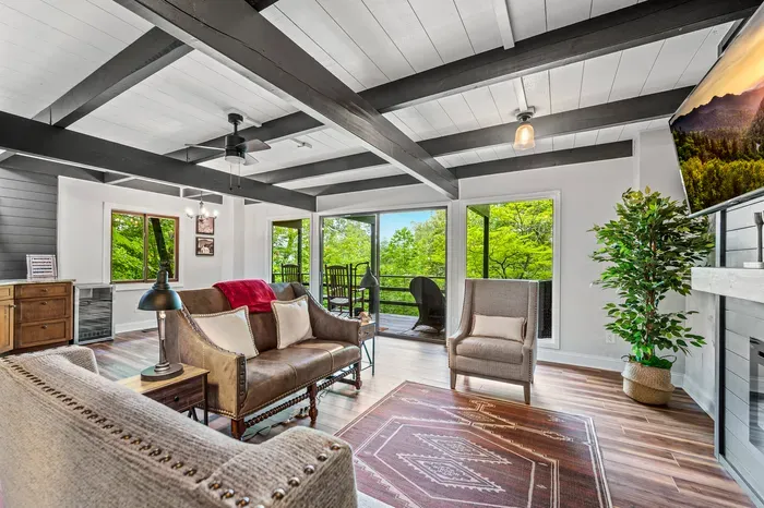 Beamed ceilings, walls of glass, and green in every window. The main living space opens straight onto the covered deck.
