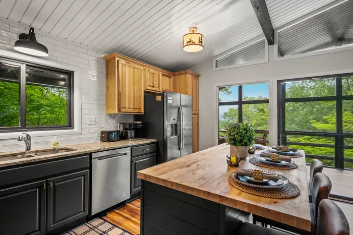 Granite counters, stainless dishwasher and range, butcher block island with the view straight ahead. Real cooking space, not a kitchenette.