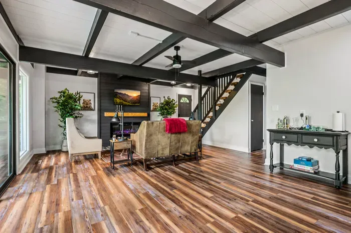 The full main level in one frame — beamed ceiling, warm wood floors, and room to spread out without tripping over each other.