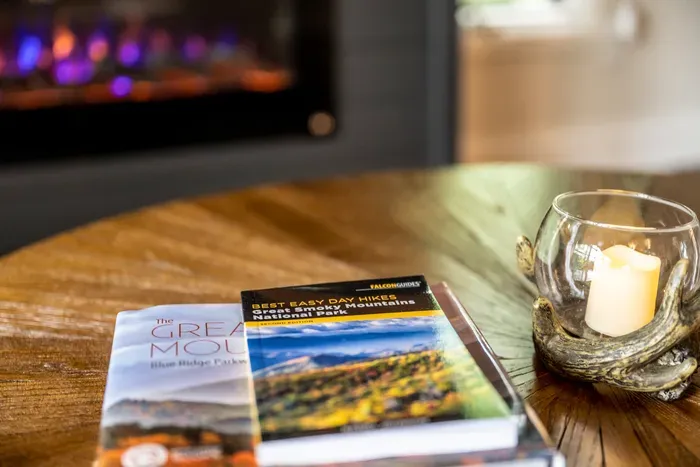 Smokies trail guides on the coffee table, fireplace already going. Plan tomorrow's hike from the warmest seat in the house.