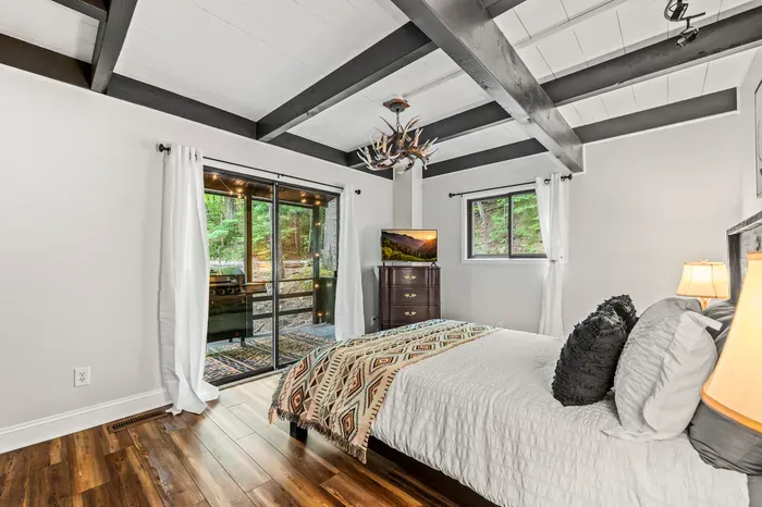 Queen bed with its own slider to the covered porch. Antler chandelier overhead, grill just outside the glass.