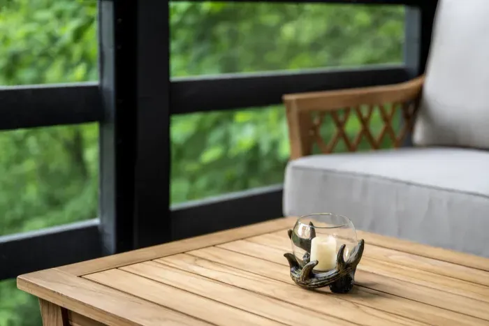 Teak table, deep-cushion seating, nothing but green through the screen. Best seat in the house is technically outside it.