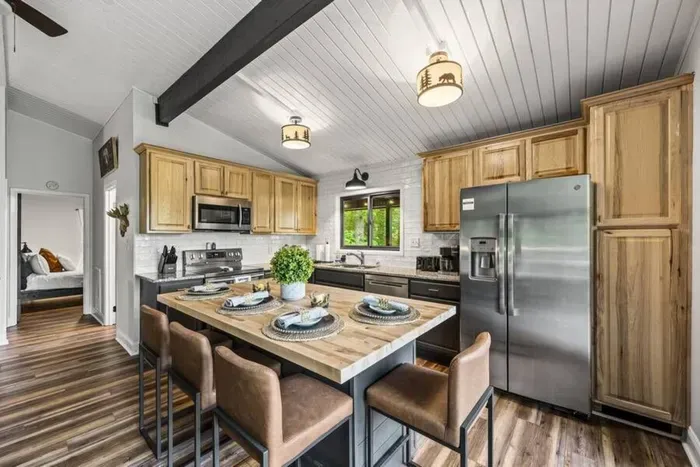 Hickory cabinets, subway tile, gas-range-sized counter space, and a bedroom right off the kitchen. Coffee station's stocked by the fridge.
