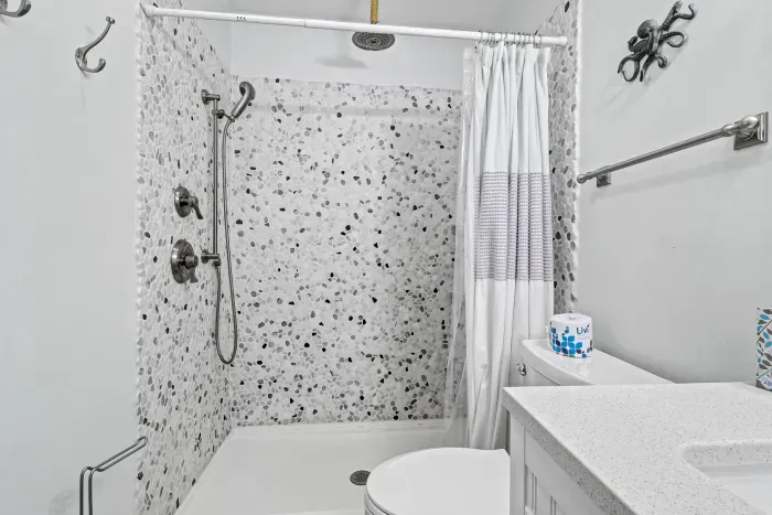 Bright modern bathroom with pebble-tile walk-in shower and coastal touches