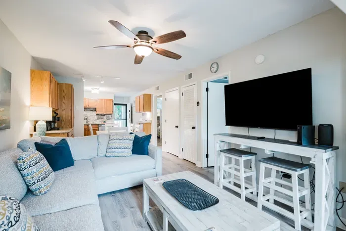 Big TV, sound bar, and a counter-height bar with stools behind the sectional. Movie night, game day, or laptop hour — the room handles all three.