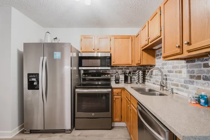 Stainless appliances, quartz counters, and a knife block that actually holds sharp knives. Coastal brick backsplash included at no extra charge.