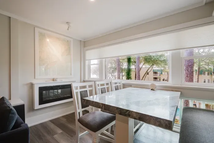 Bright dining nook with fireplace, big windows, and peaceful tree views